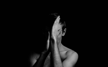 Siyah arka planda etkileyici bir duruşu olan genç bir adam.