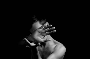 Siyah arka planda etkileyici bir duruşu olan genç bir adam.