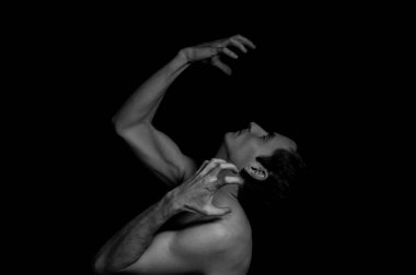 Siyah arka planda etkileyici bir duruşu olan genç bir adam.