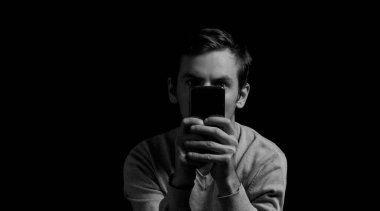 Elinde telefon olan siyah beyaz bir fotoğrafçı.