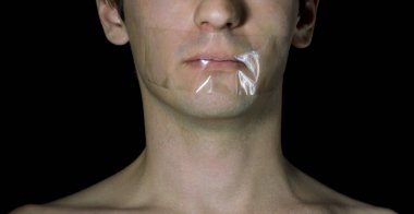 Siyah arka planda, ağzı bantlanmış bir adamın portresi.