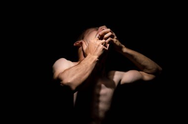 Elleriyle ağzını açıyor, dramatik bir fotoğraf.