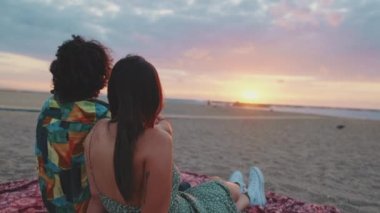 Romantik çift plajda gün doğumunu seyrederek rahatlıyor. Arka plan