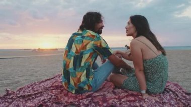 Erkek ve kadın gün doğumunda sahilde birbirleriyle konuşuyorlar.