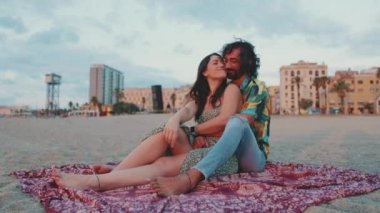 Yaklaş, kadın ve erkek sahilde sarılıyorlar ve şafağı izliyorlar.