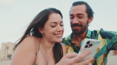 Kapatın, mutlu çift cep telefonundan fotoğraflara bakıyor.