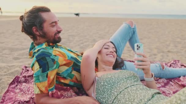 Coppia Giovane Che Rilassa Sulla Spiaggia Parlando Utilizzando Telefono Cellulare — Video Stock