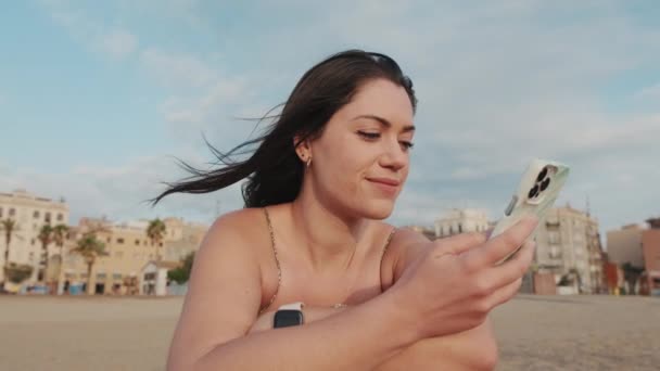 Zamknij Się Młoda Kobieta Siedzi Piaszczystej Plaży Używa Telefonu Komórkowego — Wideo stockowe