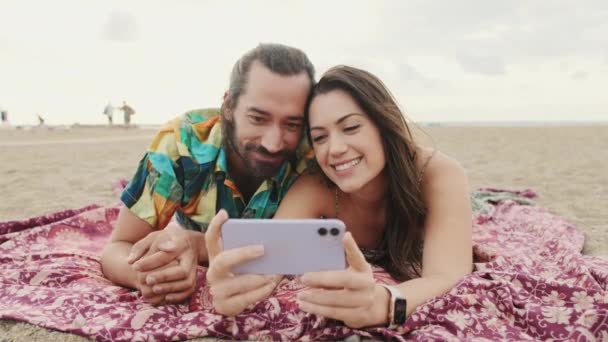 Aşık Bir Çift Kumsalda Dinleniyor Cep Telefonundan Video Fotoğraf Izliyor — Stok video