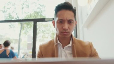 Genç işadamı kafede dizüstü bilgisayarla çalışıyor.