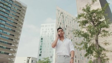 Genç işadamı, modern binalarda akıllı telefondan konuşuyor.