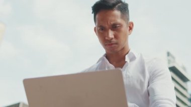 Dışarıda dizüstü bilgisayarla çalışan genç iş adamına yakın durun.