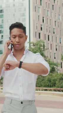 Sokakta yürüyen ve akıllı telefondan konuşan genç bir işadamı.