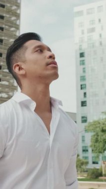 Genç işadamı modern binaların arka planında duruyor.