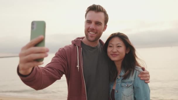 Pareja Enamorada Abrazándose Hace Selfie Mientras Está Pie Playa — Vídeo de stock