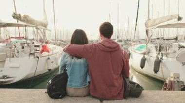 Limanda oturup yatlara bakan bir çift. Arka plan