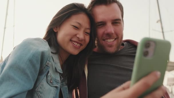 Nahaufnahme Coung Paar Mit Handy Während Auf Der Seebrücke Sitzen — Stockvideo