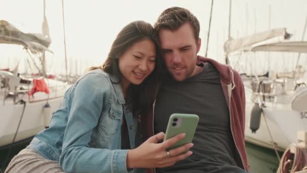 Jong Paar Met Behulp Van Mobiele Telefoon Terwijl Zitten Pier — Stockvideo