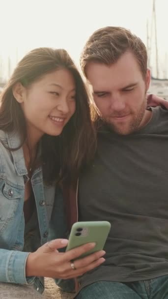 Vertical Video 坐在码头上用手机的年轻夫妇 — 图库视频影像