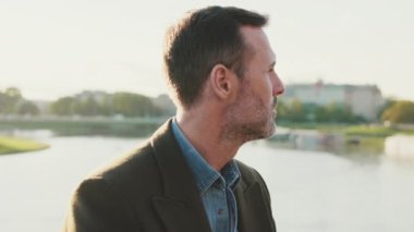 Yakından, adam nehrin arka planındaki sette otururken etrafına bakar.