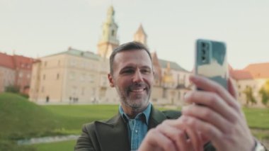 Adam eski şehrin arka planında cep telefonundan selfie çekiyor.