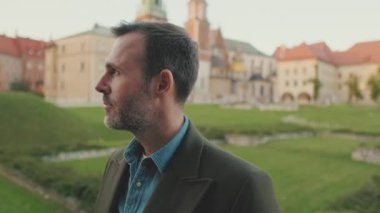 Adam kafasını çevirir ve eski şehrin arka planındaki kameraya bakar.