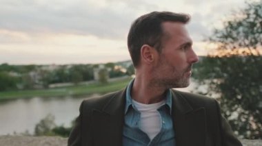 Yaklaş, adam nehir kenarında dururken etrafına bakıyor.