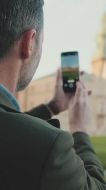 Yakın çekim, eski kentteki cep telefonuyla fotoğraf çeken bir adam. Arka plan