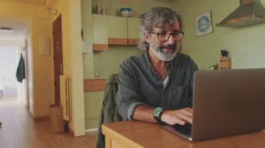 Sunbae laptopta çalışıyor. Mutfakta oturuyor.