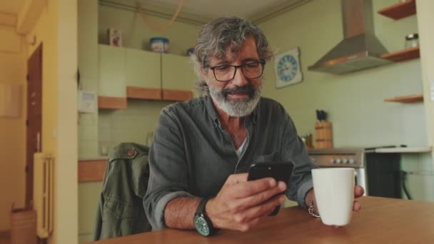 Uomo Anziano Sorpreso Beve Caffè Dalla Tazza Utilizza Telefono Cellulare — Video Stock