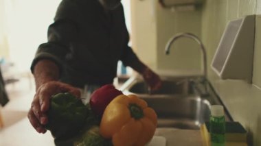 Ön planda, sebzeler, arka planda sebzeleri yıkayan adamın elleri. yumuşak odak