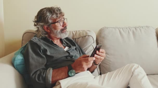 Muž Středního Věku Relaxuje Gauči Zatímco Pomocí Smartphonu Textovat — Stock video