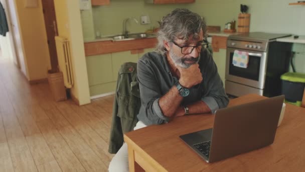 坐在家里厨房里修理笔记本电脑的老年人 — 图库视频影像