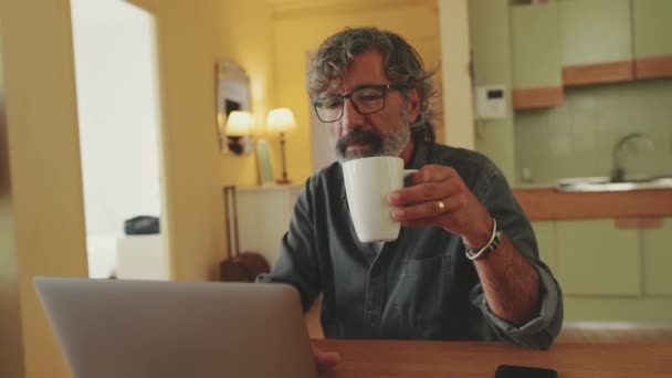 Idosos Homem Positivo Digitando Laptop Sentado Cozinha Casa — Vídeo de Stock