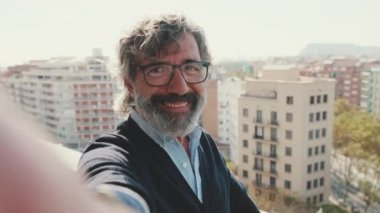 Olgun bir adamın balkonda dikilirken selfie çektiği yakın plan.