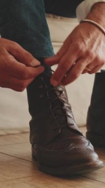 Sıradan botlar giyen, ayakkabı bağcıklarını bağlayan bir adamın bacaklarına yakın çekim.