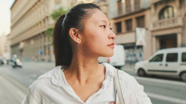 Yolun kenarında dururken cep telefonu kullanan genç bir kadın. Kız etrafına bakıyor.