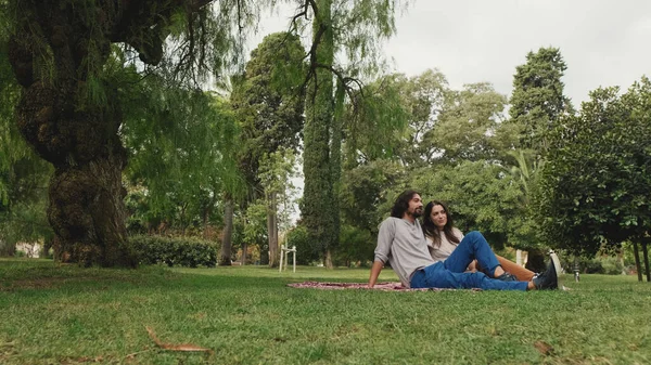 在公园里坐在毛毯上聊天的快乐夫妻 — 图库照片