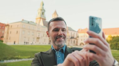 Kapatın, eski şehir arka planında cep telefonuyla görüntülü arama yapıyor.