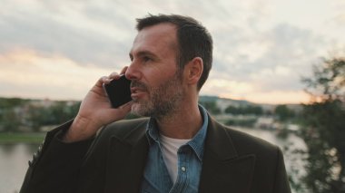 Yaklaş, adam nehrin kenarında dururken cep telefonuyla konuşuyor.