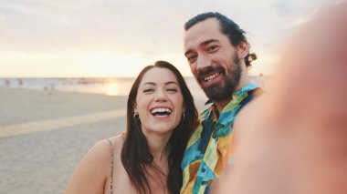 Gülen çift sahilde dikilirken görüntülü arama yapıyor.