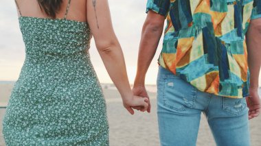 Deniz altyapısında el ele tutuşan genç bir çift. Arka plan