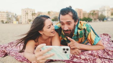 Kadın ve erkek sahilde cep telefonuyla video görüşmesi yapıyor.