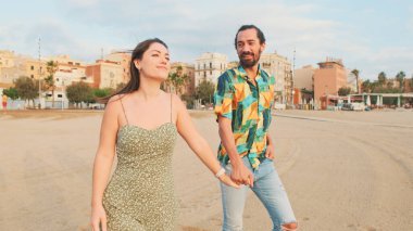 Birbirini seven bir çift kumsalda yürüyor ve sarılıyorlar.