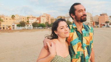 Birbirini seven bir çift kumsalda yürüyor ve sarılıyorlar.