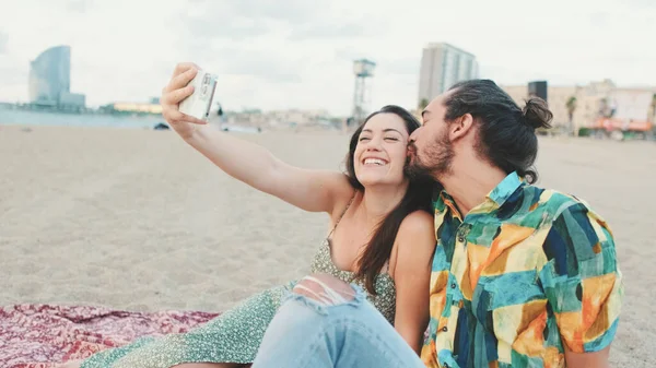 ビーチに座っている間 幸せなカップルは携帯電話で自撮り — ストック写真