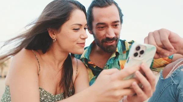 Pareja Joven Utiliza Teléfono Móvil Mientras Está Sentado Playa Fondo —  Fotos de Stock