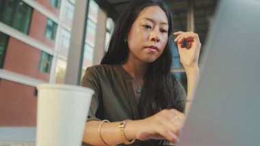 Dizüstü bilgisayarda çalışan ve kahve içen genç bir kadın.