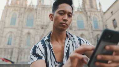 Basamaklardaki genç turist, arka planda otururken cep telefonu kullanıyor