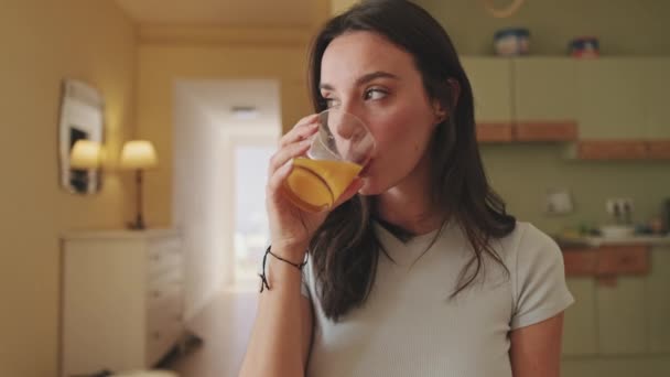 靠近点 年轻女人坐在厨房里喝橙汁 — 图库视频影像